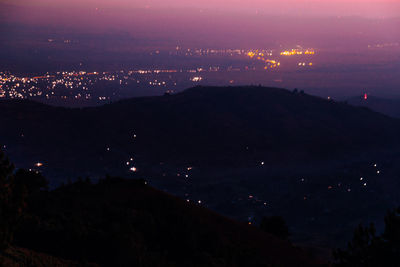 Aerial view of illuminated cityscape against sky at sunset