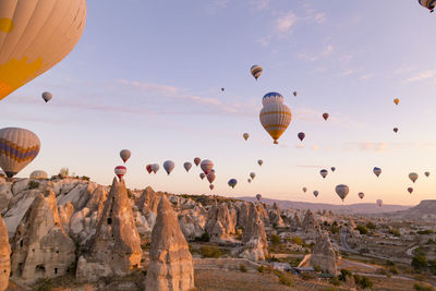 Hot air balloons flying over rocks against sky