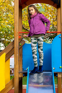 Portrait of girl standing on slide at playground