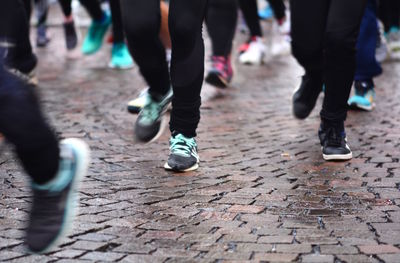 Low section of people walking on wet street in city