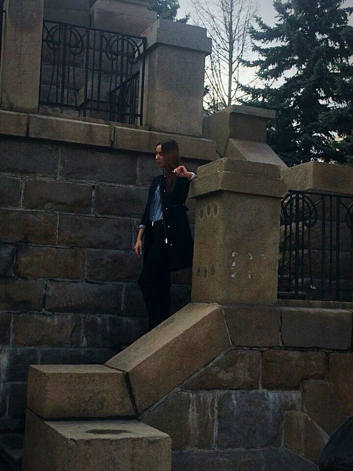 YOUNG WOMAN STANDING ON RAILING OF BUILDING