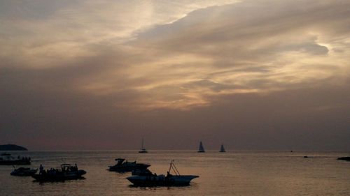 Sailboats sailing in sea against sky during sunset