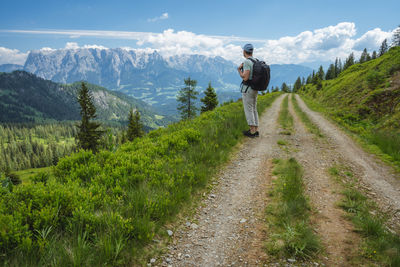Rear view of man standing on mountain against sky