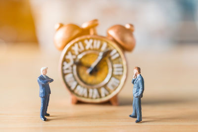 High angle view of figurines with clock on wooden table