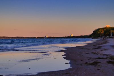 Scenic view of beach against clear sky during sunset