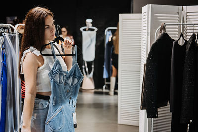 Young brunette latina attractive woman shopper choosing new jeans cloth at store.