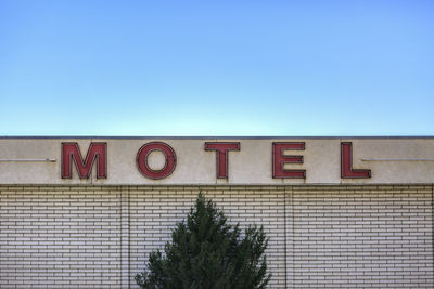 Low angle view of text on wall against clear sky