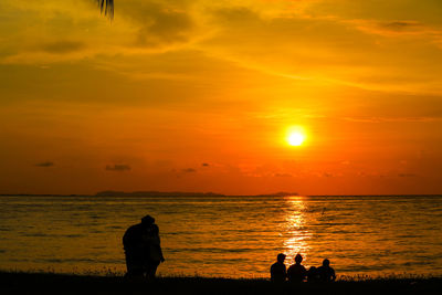Silhouette people on beach against sky during sunset