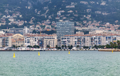 Sailboats in sea against buildings in city