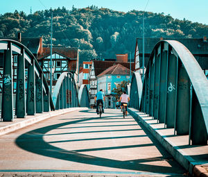 Rear view of people walking on footbridge amidst buildings