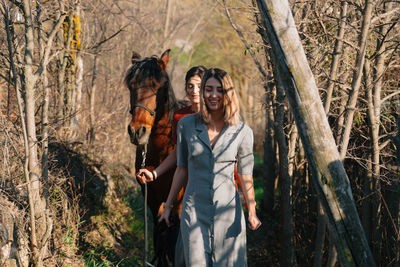 Friends standing by tree trunk in forest