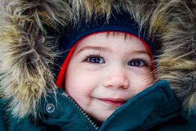 Close-up portrait of cute boy in fur hood