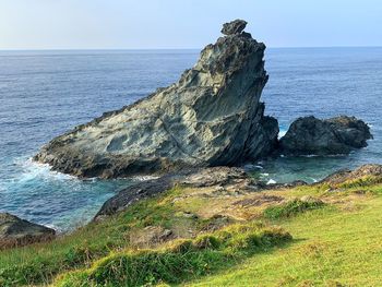 Rock formation on sea shore against sky