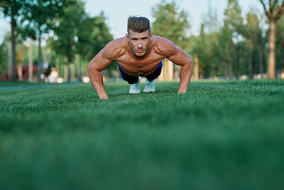 Portrait of young man exercising on field