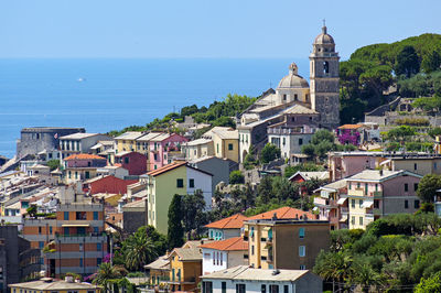 Buildings in city by sea against sky