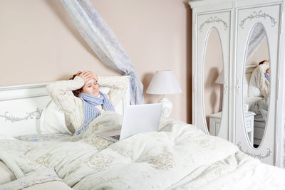 Midsection of woman relaxing on bed at home