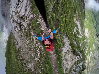 Directly above view of man holding monopod sitting on mountain peak