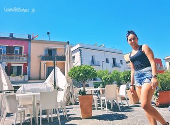 Full length of happy woman standing against blue sky