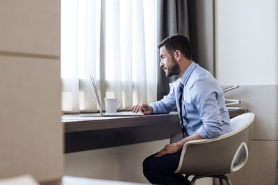 Side view of businessman using laptop in hotel room