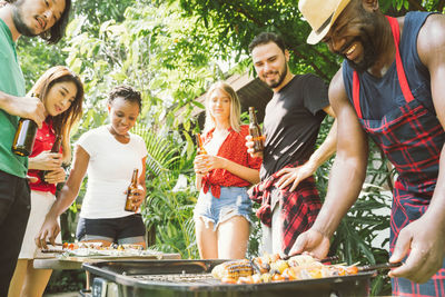 Man with friends preparing food on barbecue grill