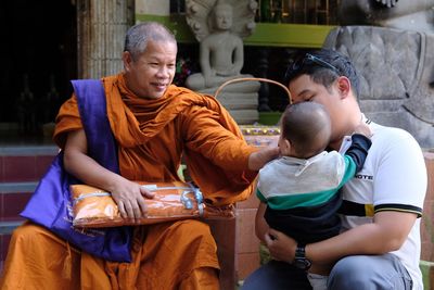 Monk playing with girl held by father