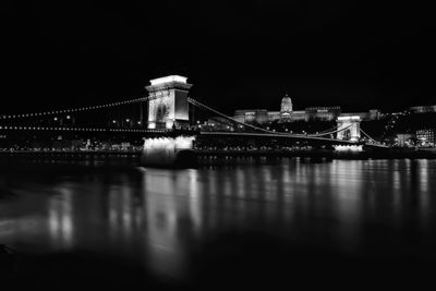 Illuminated bridge over river at night