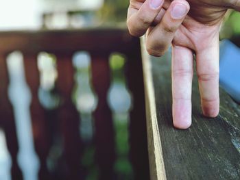 Close-up of hands holding railing against blurred background