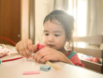 Portrait of cute girl holding table at home