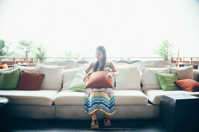 Full length of woman relaxing on sofa