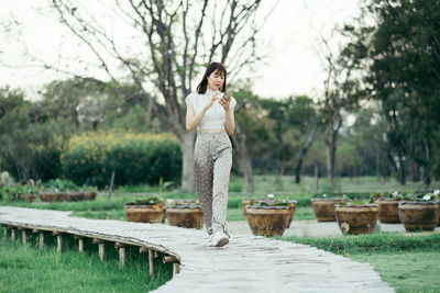 Woman standing by plants against trees