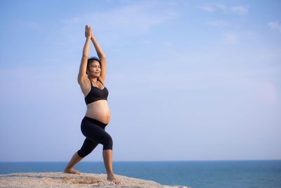 Full length of young woman in sea against sky