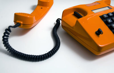 Close-up of orange telephone on table