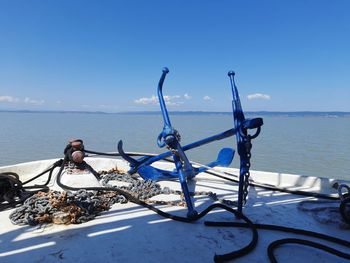 Scenic view of lake, anchor and chains against blue sky