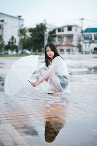 Portrait of young woman with umbrella sitting outdoors