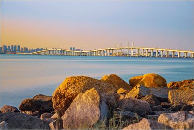 Bridge over sea against sky during sunset