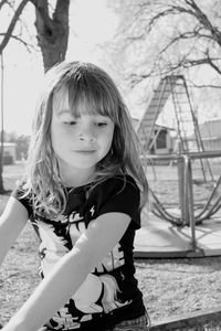 Smiling cute girl looking down while standing against play equipment at park