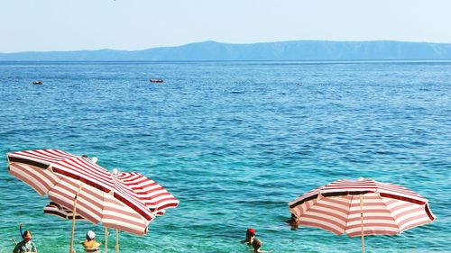 People enjoying in sea against clear sky