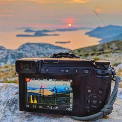 Close-up of camera against sky during sunset