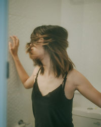 Side view of young woman looking through window