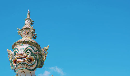 Low angle view of statue against blue sky and building