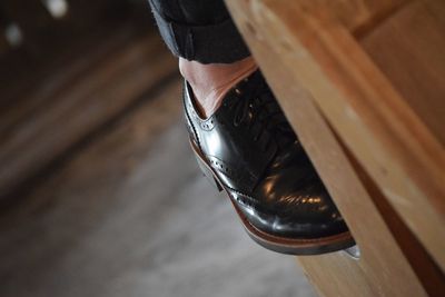 Low section of man wearing shoe on table at home