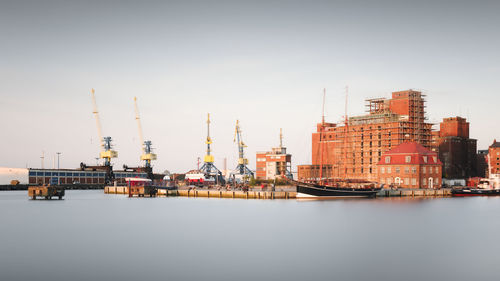 Commercial dock by sea against clear sky