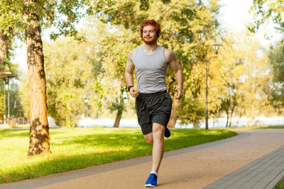 Portrait of young man running in park