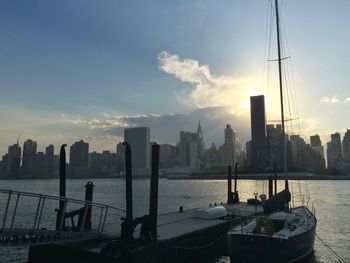 View of city at waterfront against cloudy sky