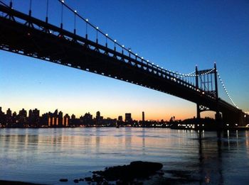 Suspension bridge over river at sunset