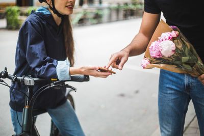 Midsection of woman holding smart phone on street