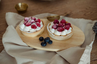 Airy cakes with raspberries on a wooden tray on the table.
