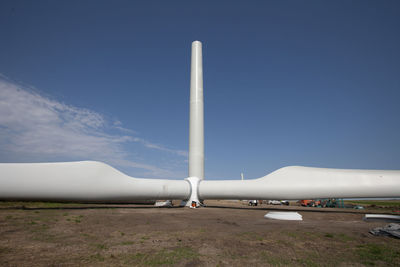 Wind turbines on landscape against clear blue sky during sunny day