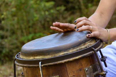 Cropped hands of woman playing drum outdoors