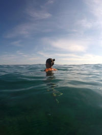 Rear view of woman swimming in adriatic sea on sunny day against sky